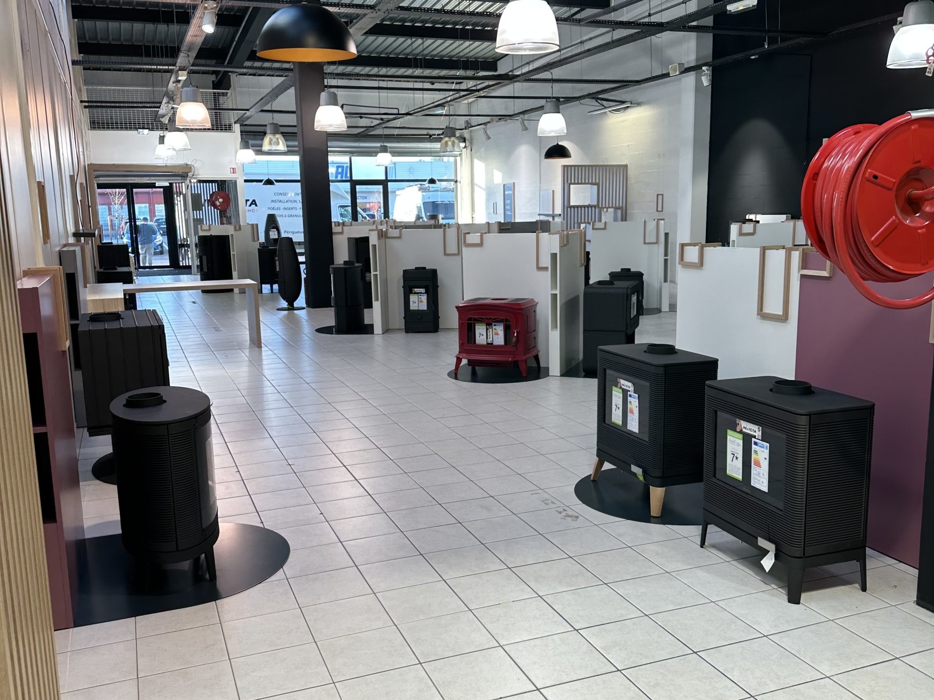 Salle d'exposition avec poêles et luminaires modernes.
